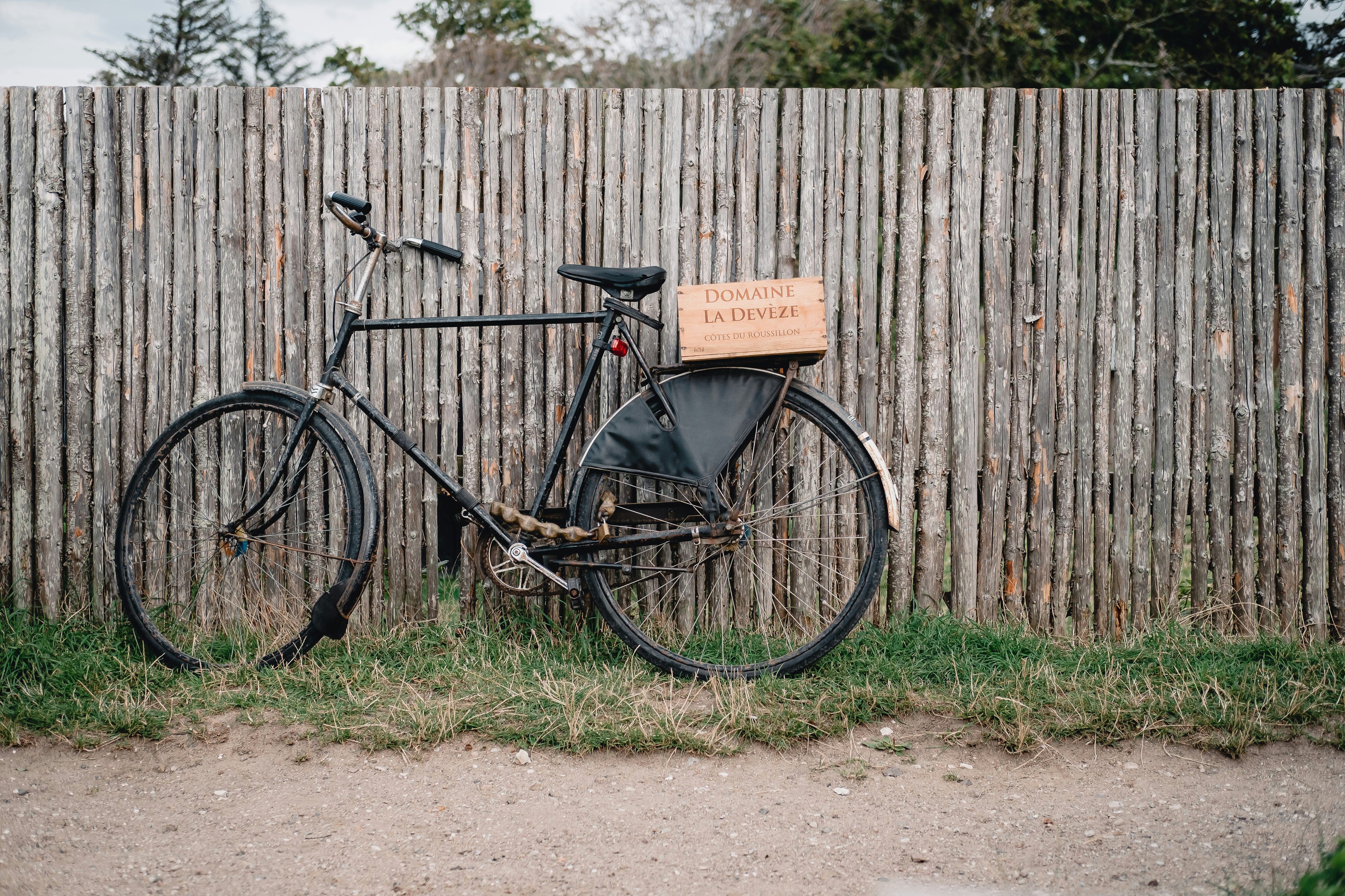 black commuter bike beside wooden fence